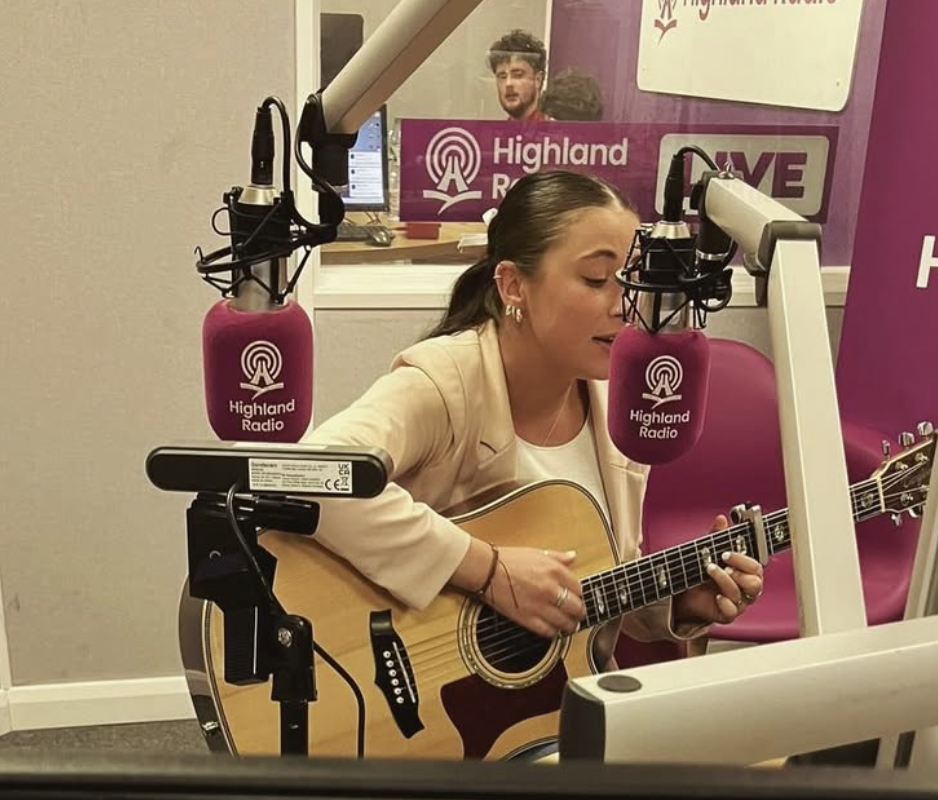 Leanne playing acoustic guitar live at Highland Radio